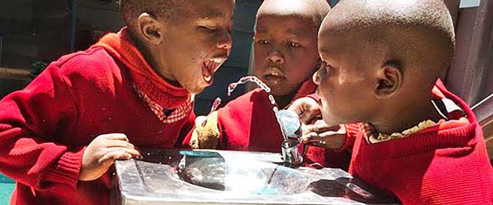Kids drinking clean water from a drinking fountain