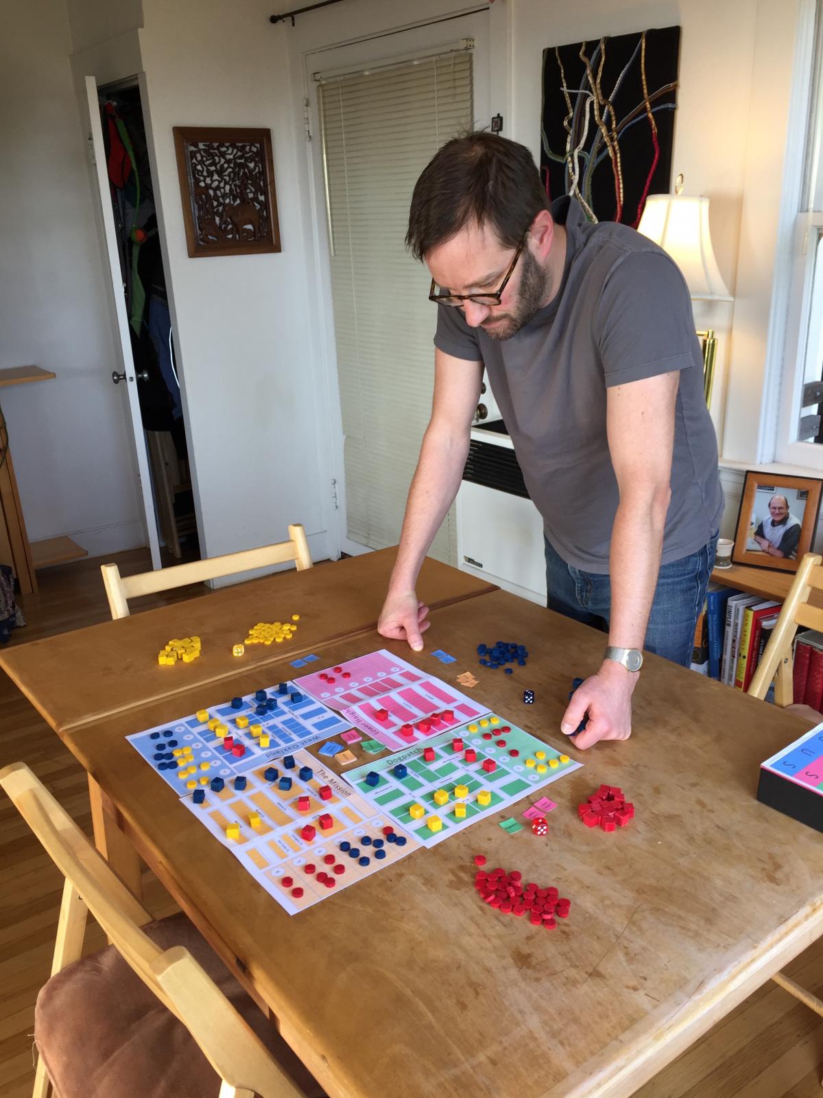 Daniel Acland standing above a board game 