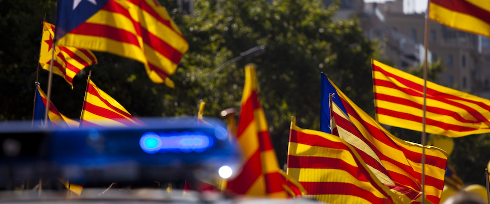 People holding Catalonian flags near a cop car
