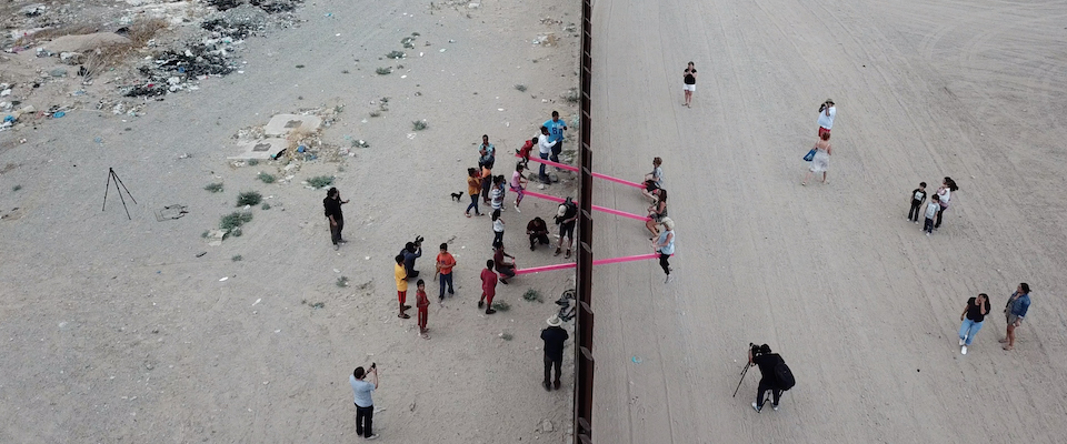Aerial photograph of kids playing on seesaw at the US Mexico border.