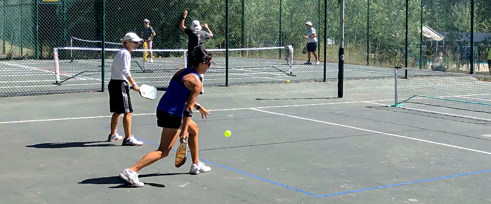 Pickleball player swinging whiffleball