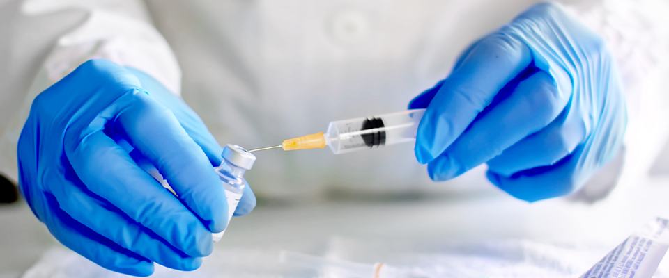 Photo of a vaccine being drawn out of a vial with a syringe.