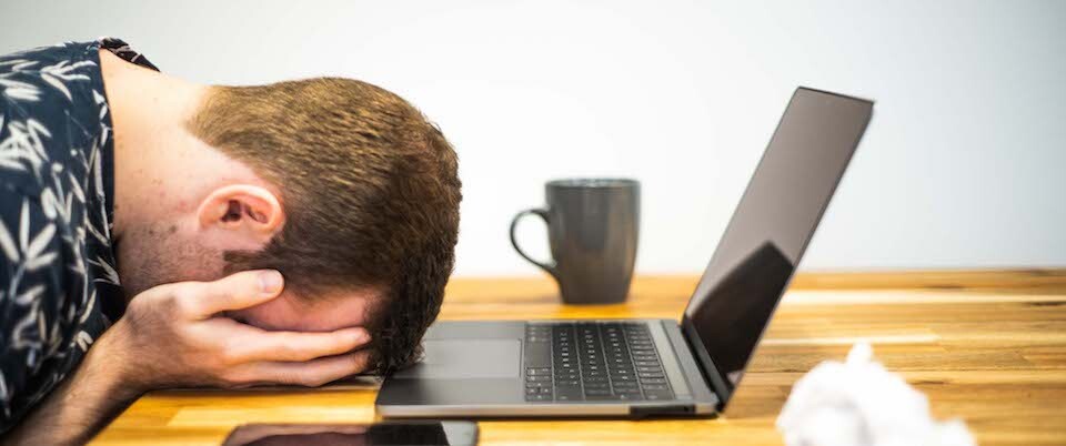 Man facedown in front of a laptop