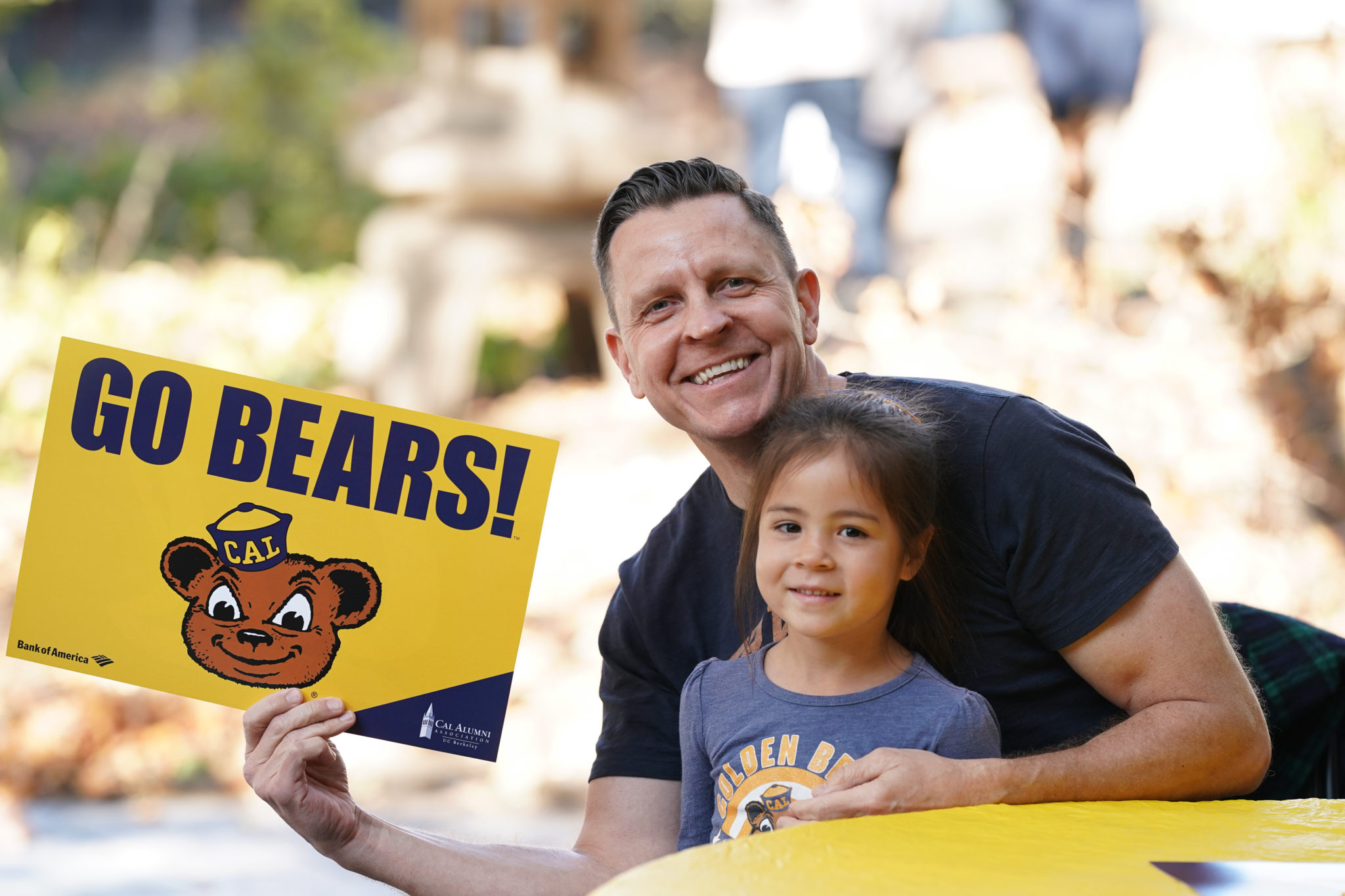Man with young child holding Go Bears sign