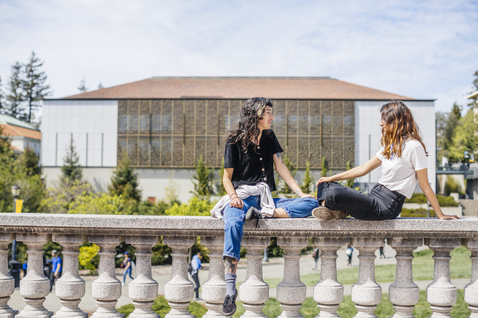 Students chat on Doe Library steps, with Asian Library in background