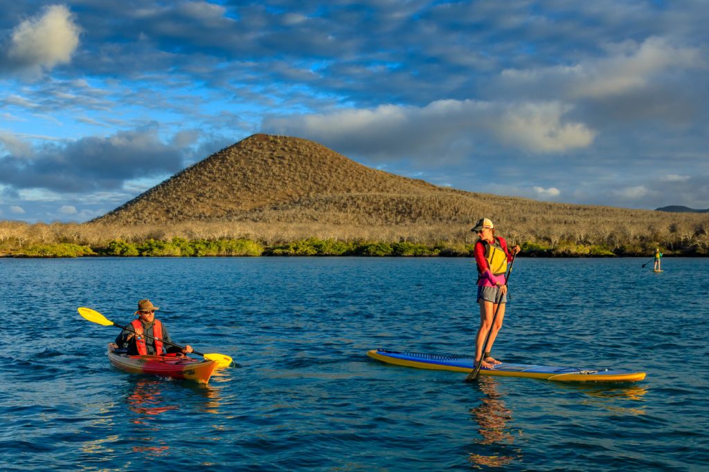 Stand-up Paddle boarders with a kayaker on Floreana Island, Galapagos Islands National Park, Ecuador