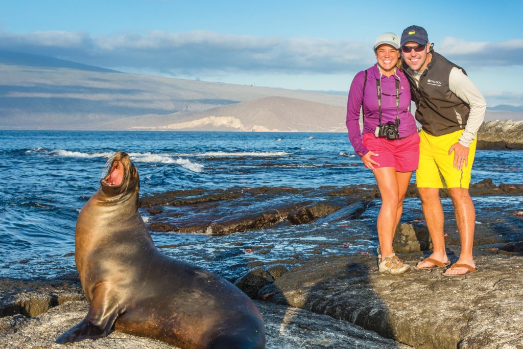 Travelers next to a sea lion on Isabela Island, Galapagos National Park, Galapagos, Ecuador