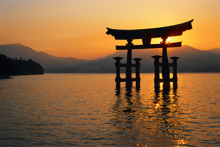 Traditional torii gate in water at sunset