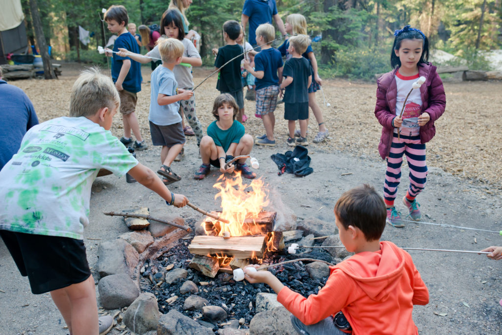 kids gathered around the campfire making smores