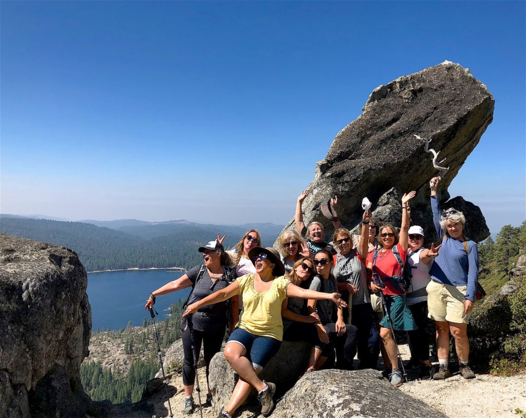 Group of women pose at a vista at the peak of a hike