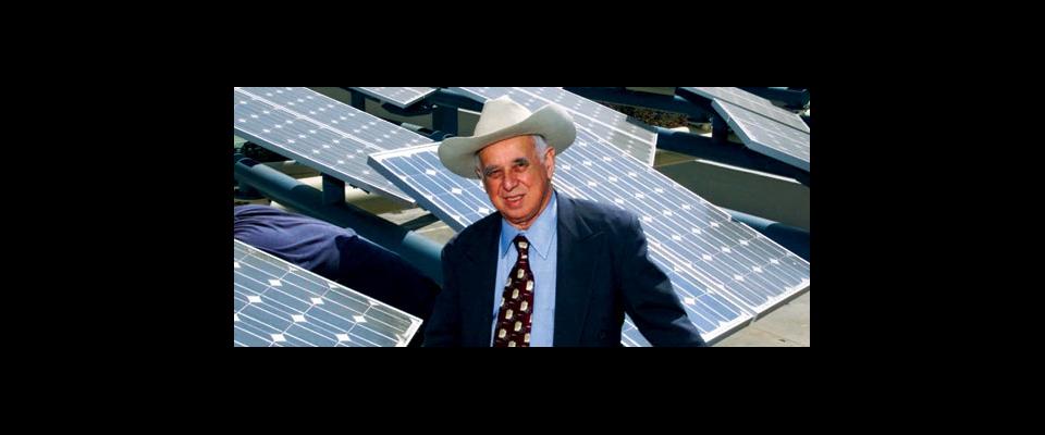 man in cowboy hat in front of solar panels