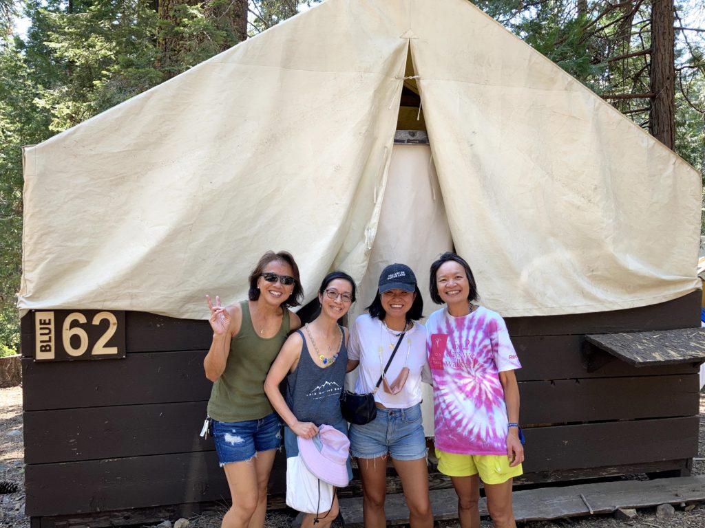 four women posing in front of tent cabin