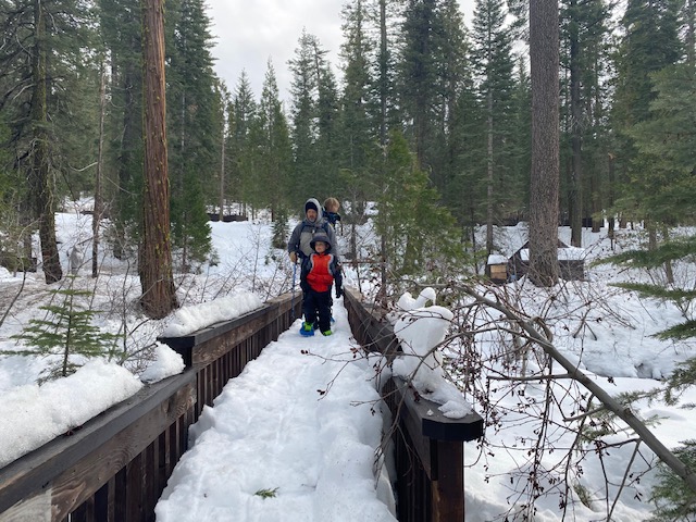 family standing on snow covered bridge