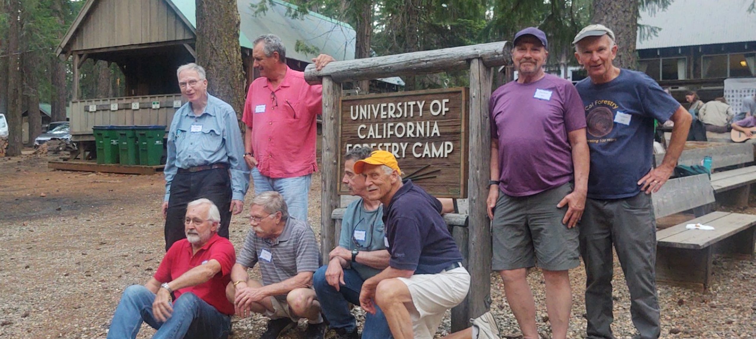 Men next to a sign and cabins