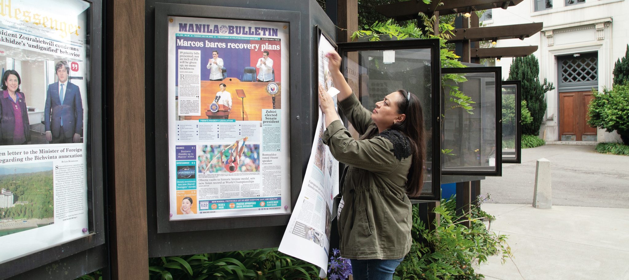 Woman puts up newspaper in display case
