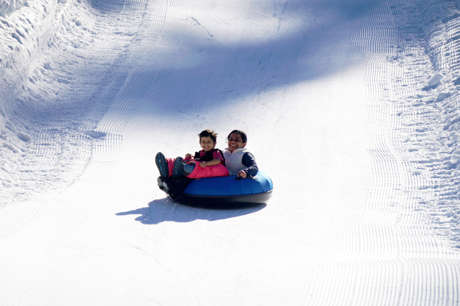 two kids slide in innertube on snow