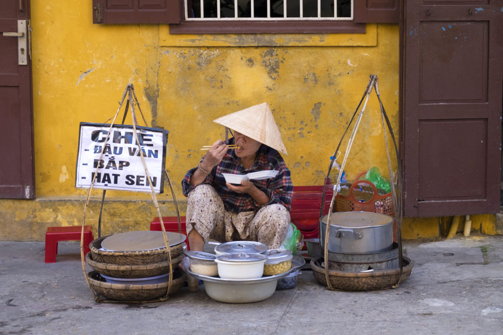 A street vendor eating her lunch in the old quarter of Hoi An Vietnam