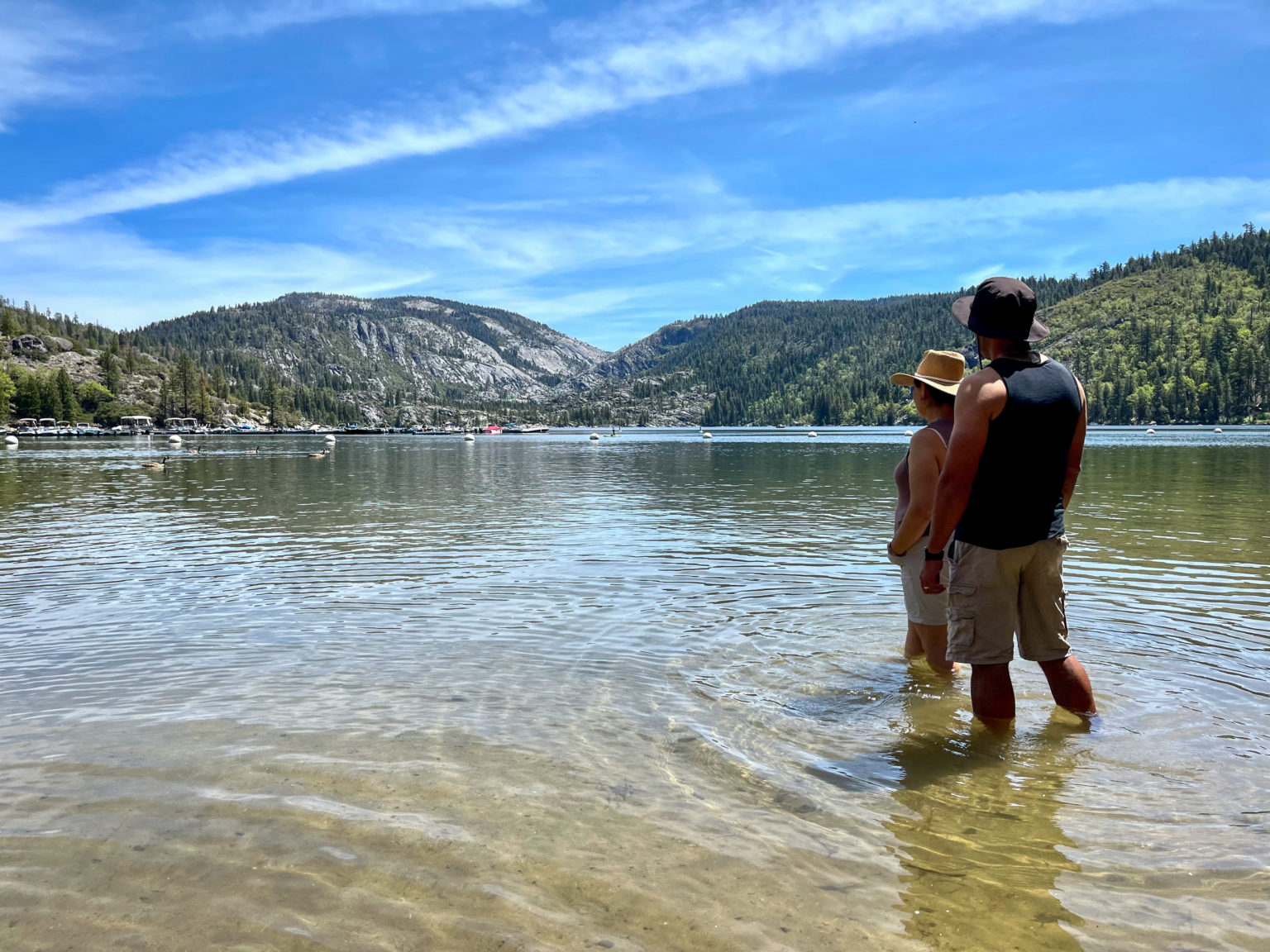 Two people standing in a lake admiring the mountains