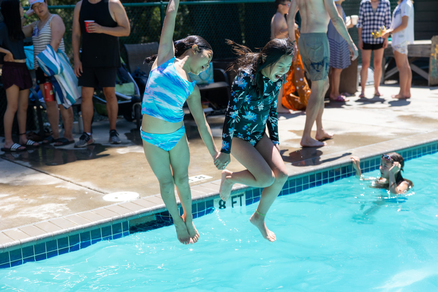 two children jumping into a pool