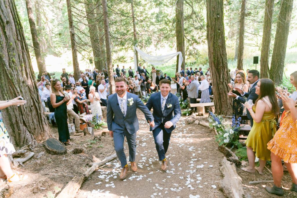 Mikey and Stephen walk out of their outdoor wedding ceremony hand-in-hand.
