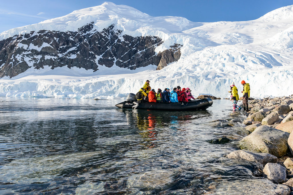 Travelers emerge from zodiac boat to step foot on Antarctic continent