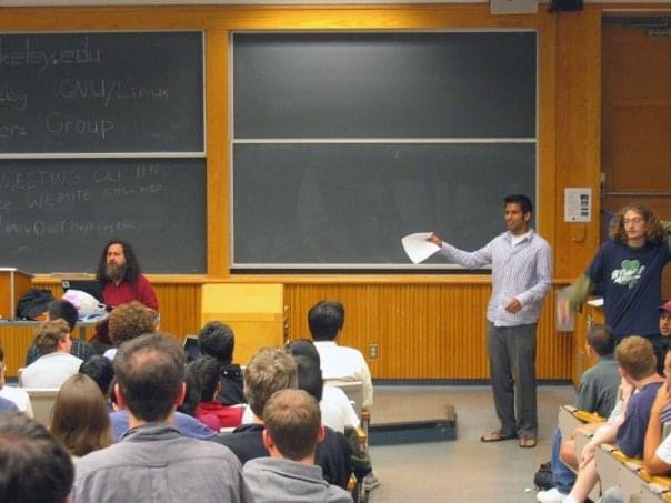 Ryan Waliany stands in front of a blackboard instructing a room full of students. 