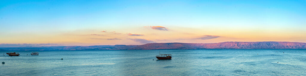 Sunset view of a wooden boat floating on the sea of galilee, Israel