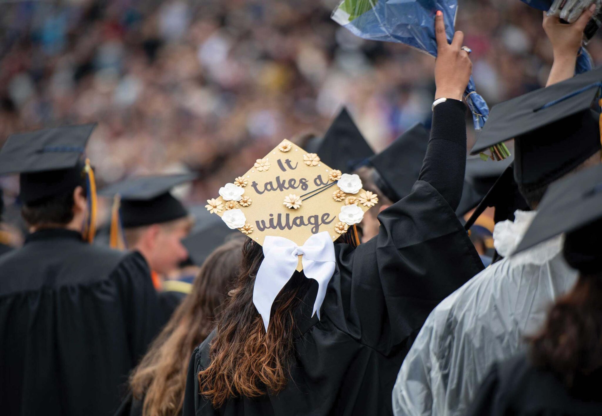 back of grad cap reading it takes a village