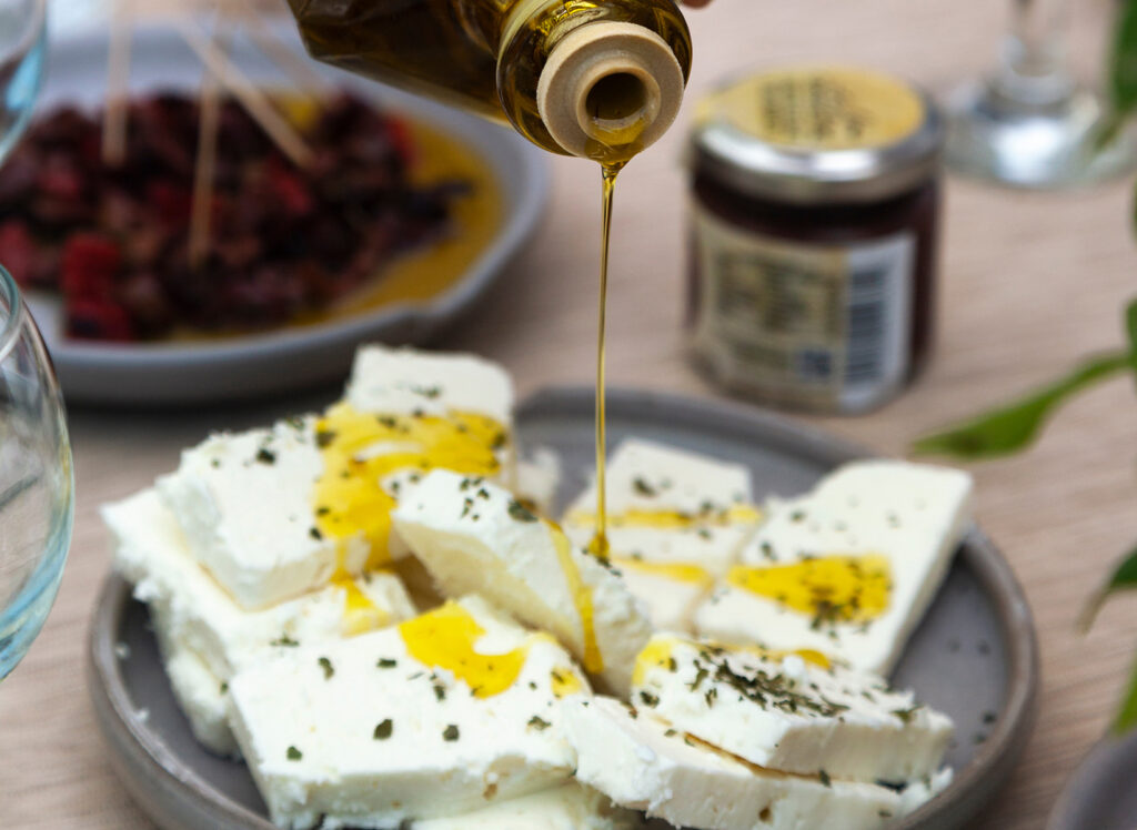 Olive oil is drizzled over slices of feta cheese