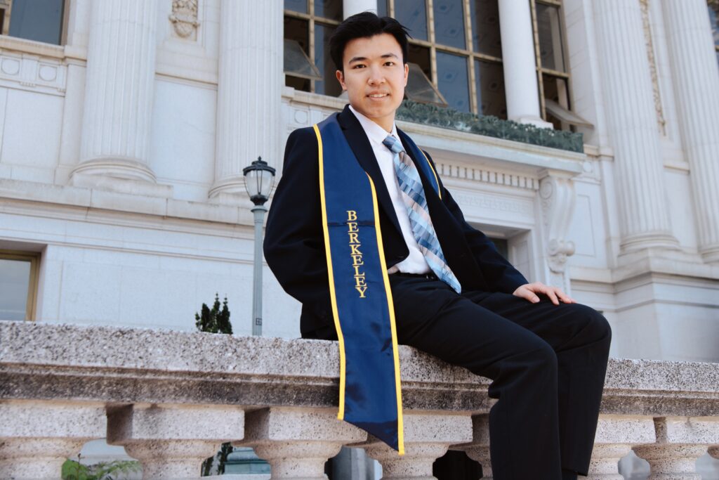 Jayden Zheng poses outside Bancroft Library wearing his graduation stole.