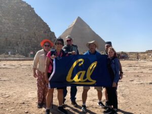 travelers stand in front of the pyramids in egypt holding a Cal banner