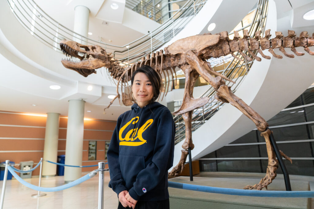 Sharon Ku poses in front of one of the dinosaur fossils featured at the Valley Life Sciences Building. 