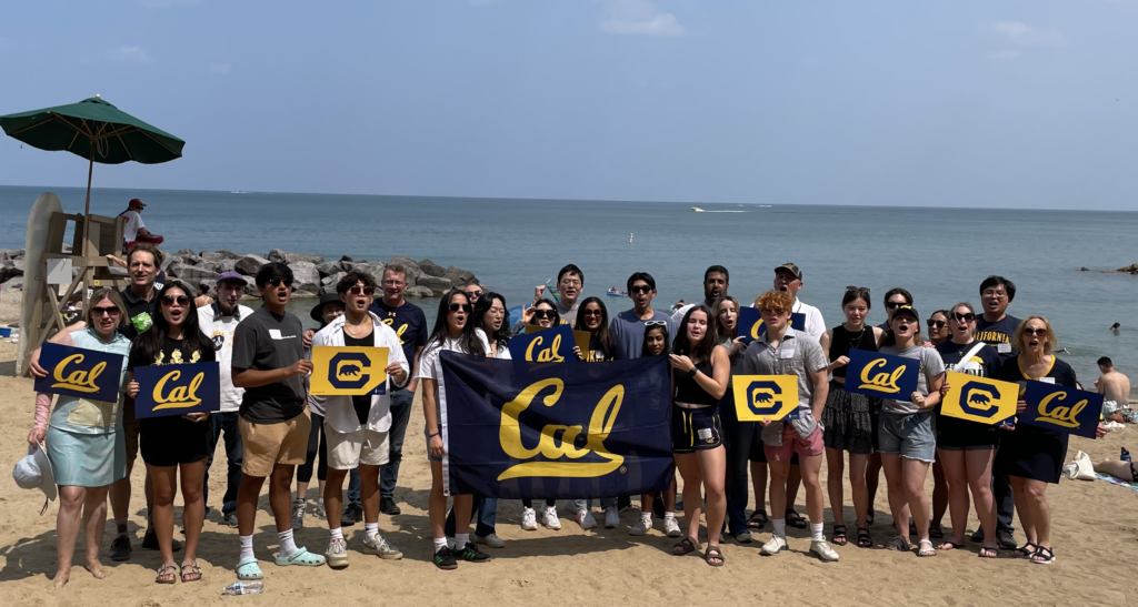 Attendees at the Cal Alumni Club of Chicago Summer Welcome Party pose at the beach with Cal banners. 