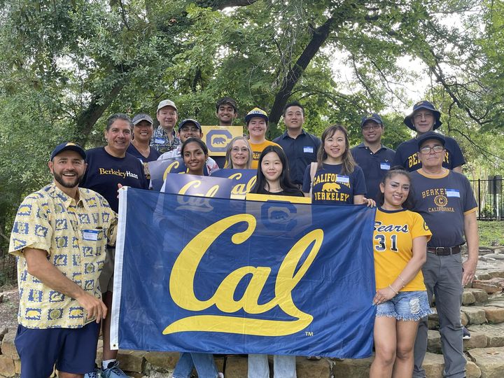 Attendees at the Cal Alumni Club of Houston Summer Welcome Party pose with a Cal flag. 