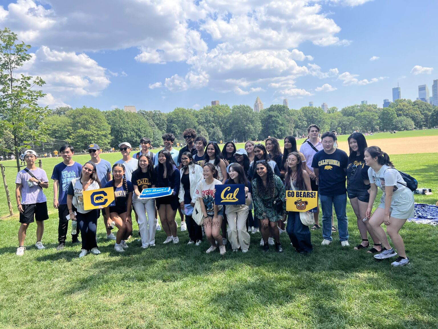 Attendees at the Cal Alumni Club of New York Summer Welcome Picnic pose with Cal signs.