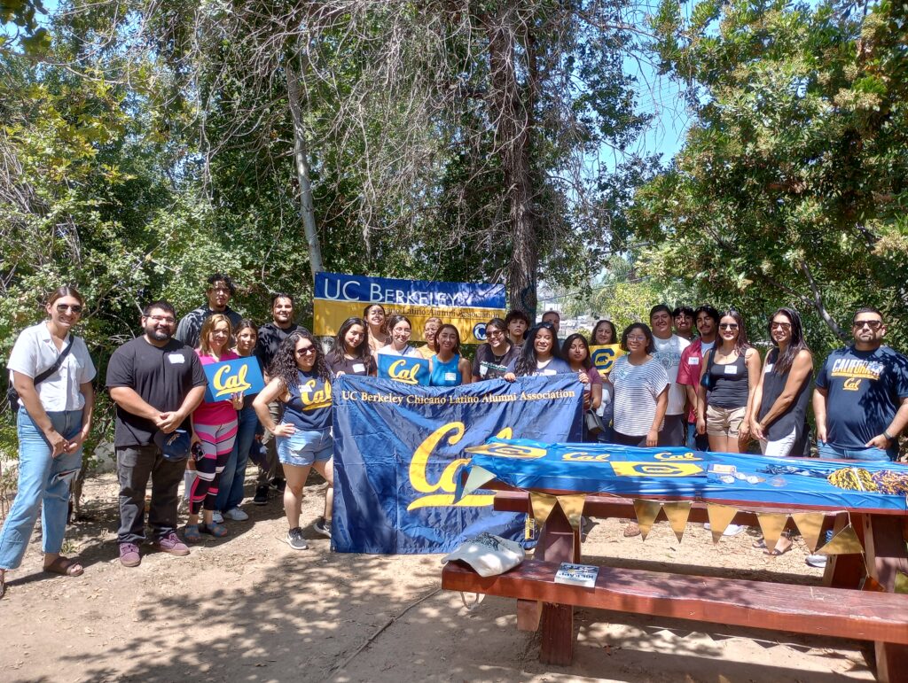 Attendees at the Chicanx Latinx Alumni Association Somos Berkeley Welcome Party in Los Angeles pose with Cal flags. 