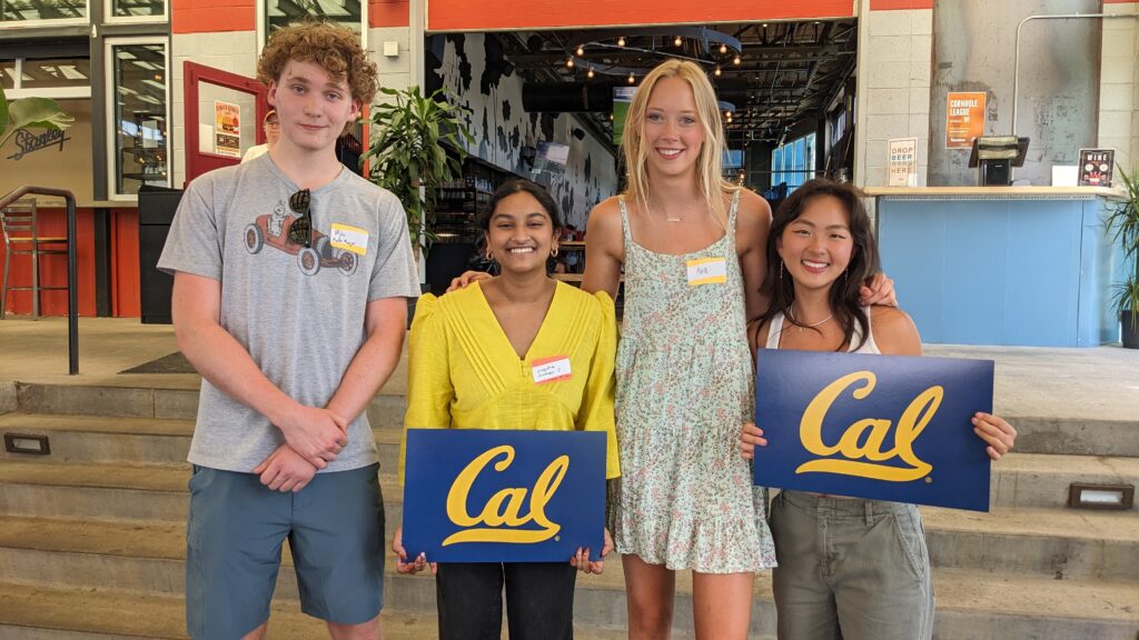 Students at the Rocky Mountain Golden Bears New Student Welcome Party pose with Cal banners. 