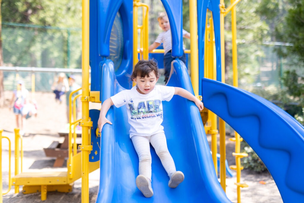 a young girl sliding down a blue slide
