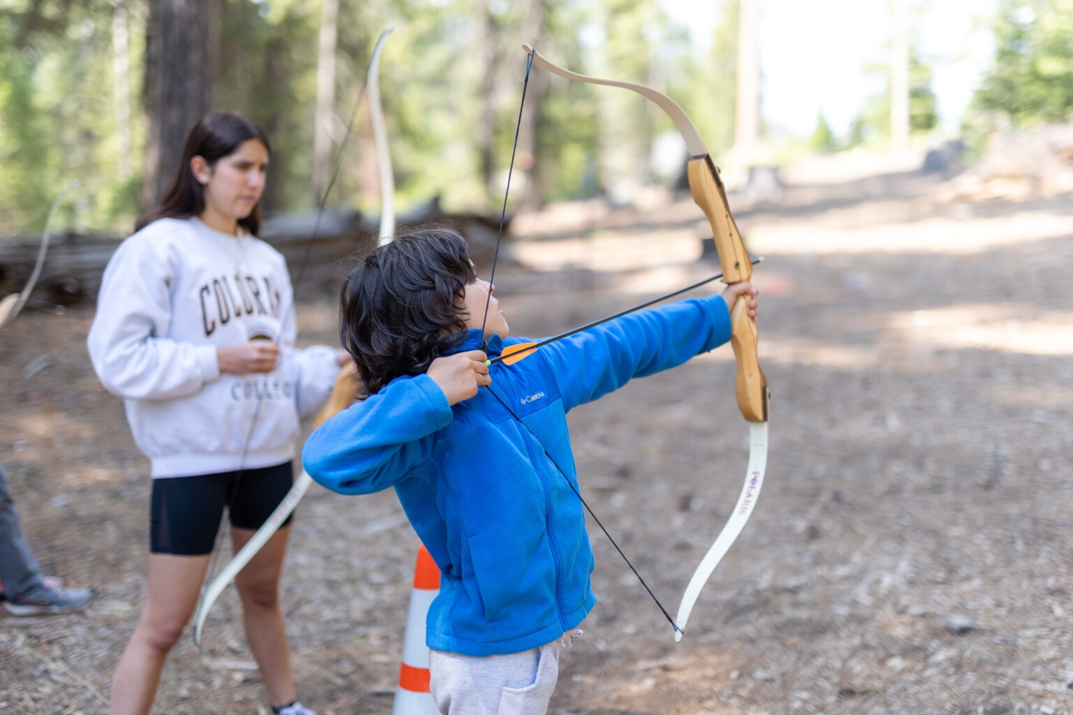 a child pulling back the string on an archery bow