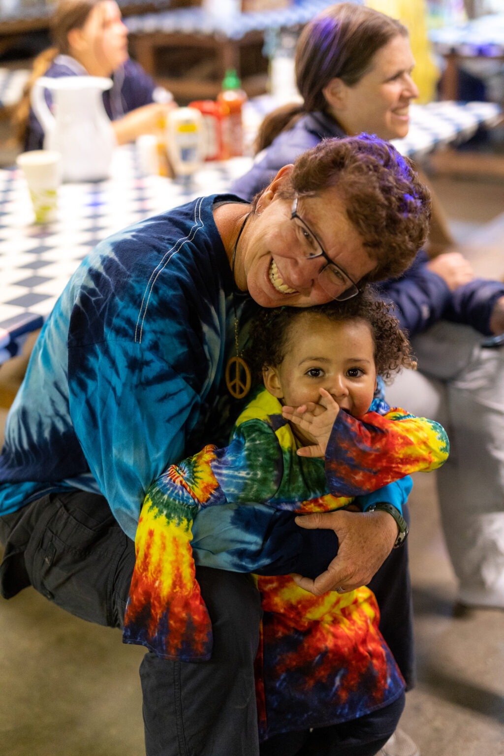 a woman hugging a toddler, both dressed in tie dye