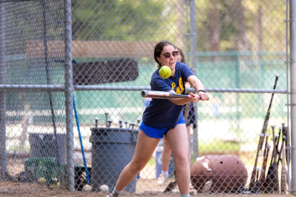 A person up to bat at softball swinging at the ball