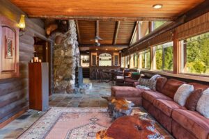 The interiors of a cabin with a stone fireplace and couch