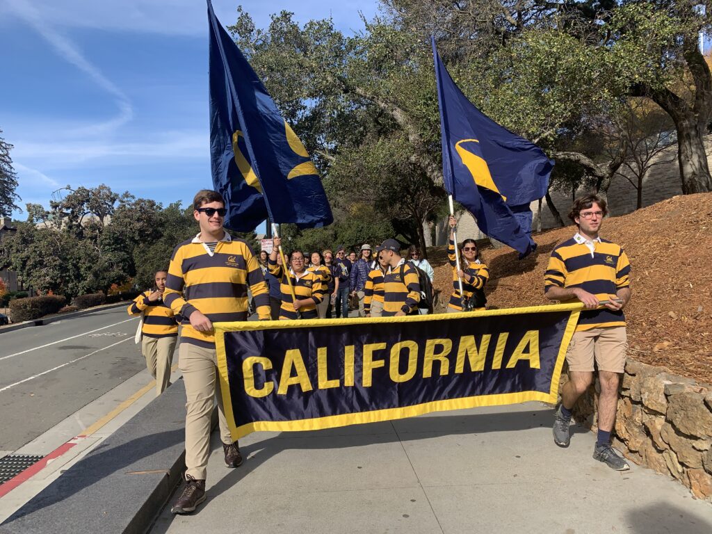 UC Rally Committee members walk through campus with Cal flags. 