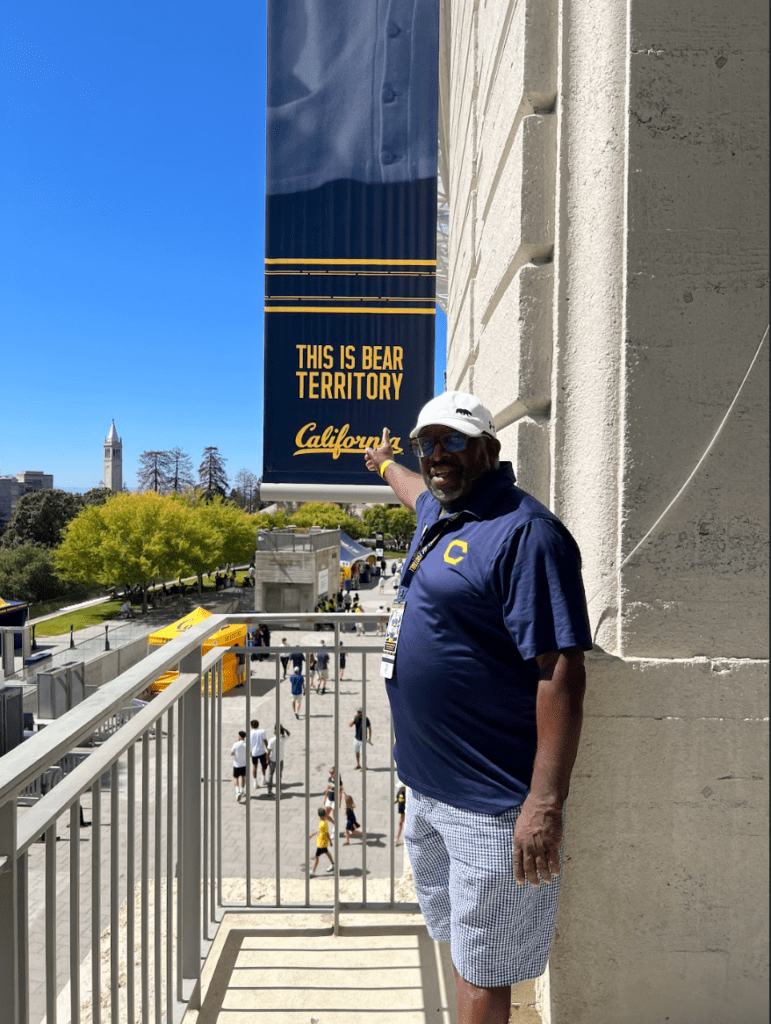 Ahmad Anderson stands outside of Memorial Stadium next to a banner reading bear territory.