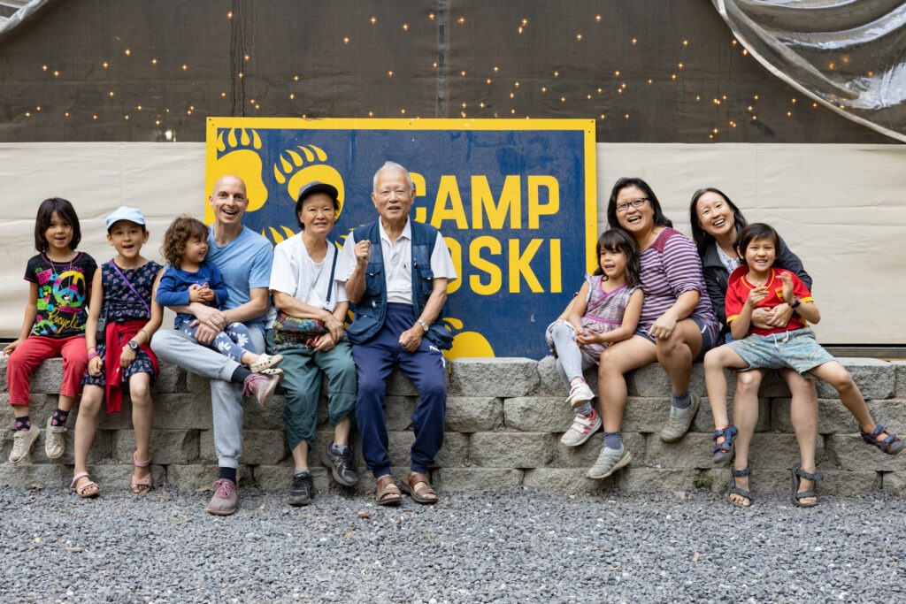 A family poses in front of a Camp Oski banner.