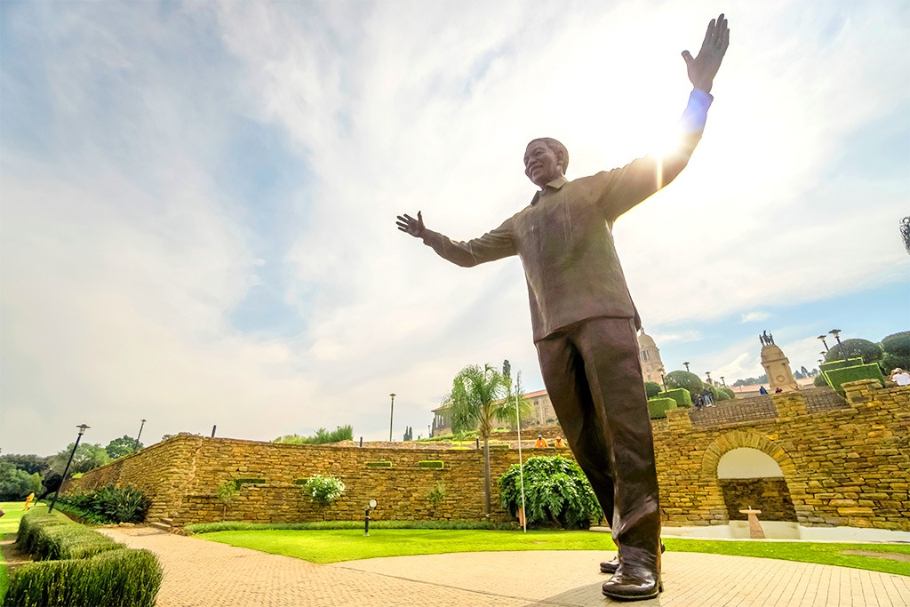 A statue of Nelson Mandela standing with his arms outstretched