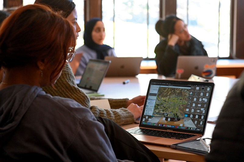 Students in HRC’s Investigations Lab sitting around a table with laptops open, engaged in a collaborative study session.