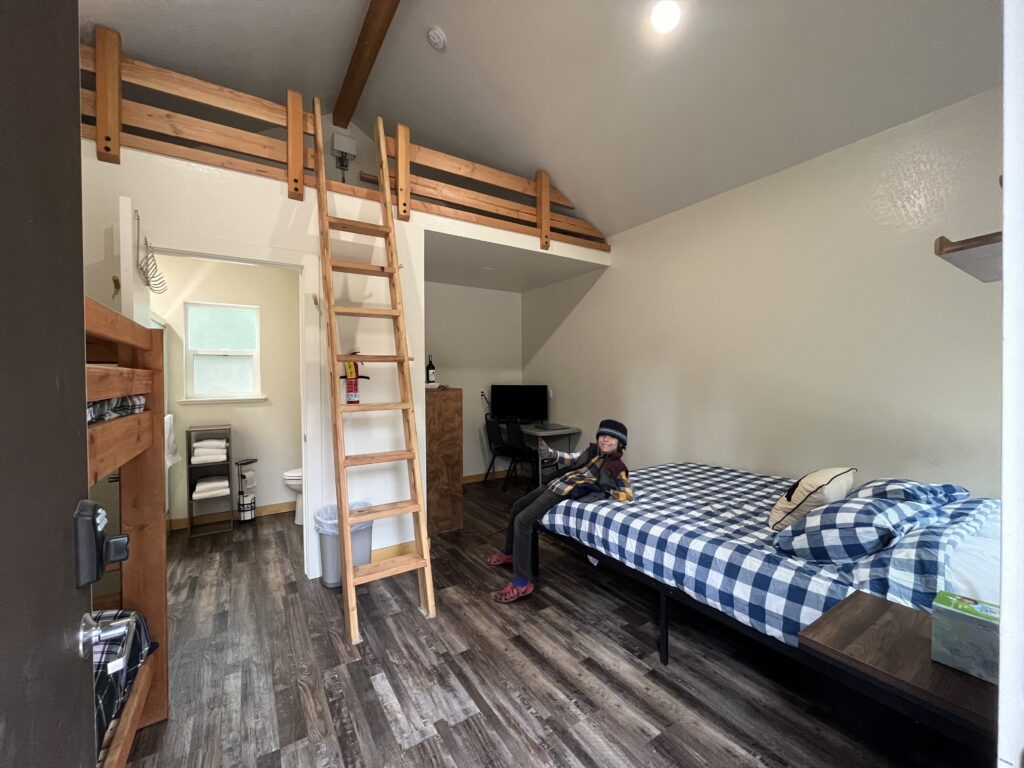 Interior of an Oski Cabin with child sitting on the queen bed.