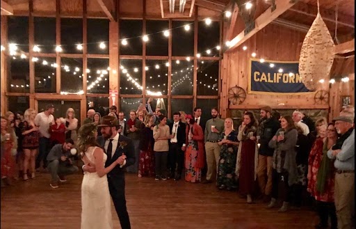 A bride and groom sharing a dance with onlookers in the lodge at the Lair