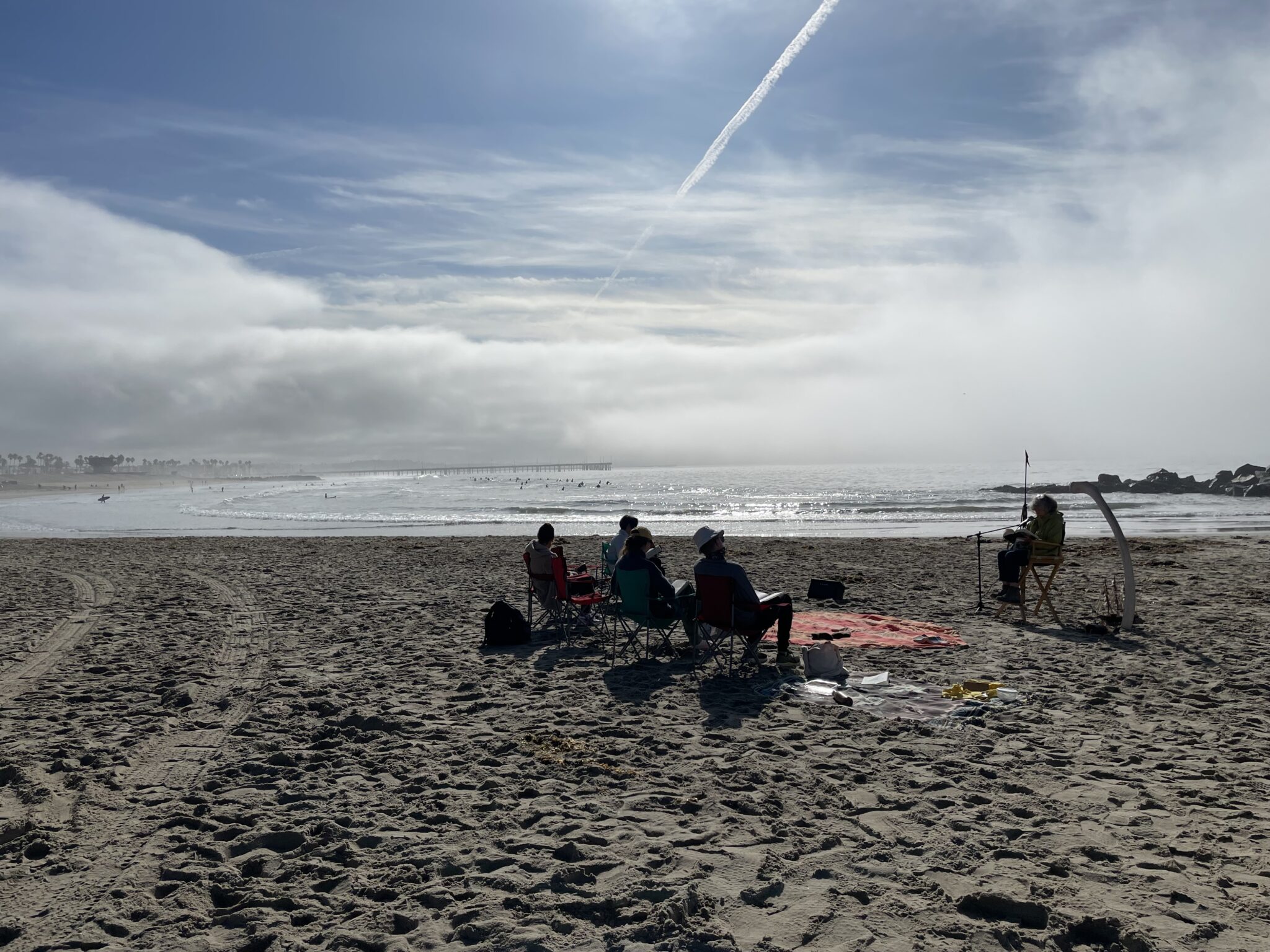 A group of people sitting on a sandy beach